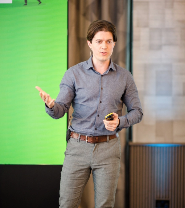 Ed Darling on stage gesturing while delivering public speaking training to a professional audience