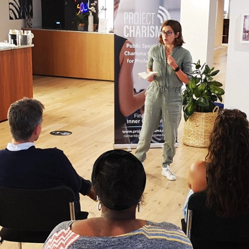 Woman practising public speaking skills in front of a small audience during a Project Charisma training course